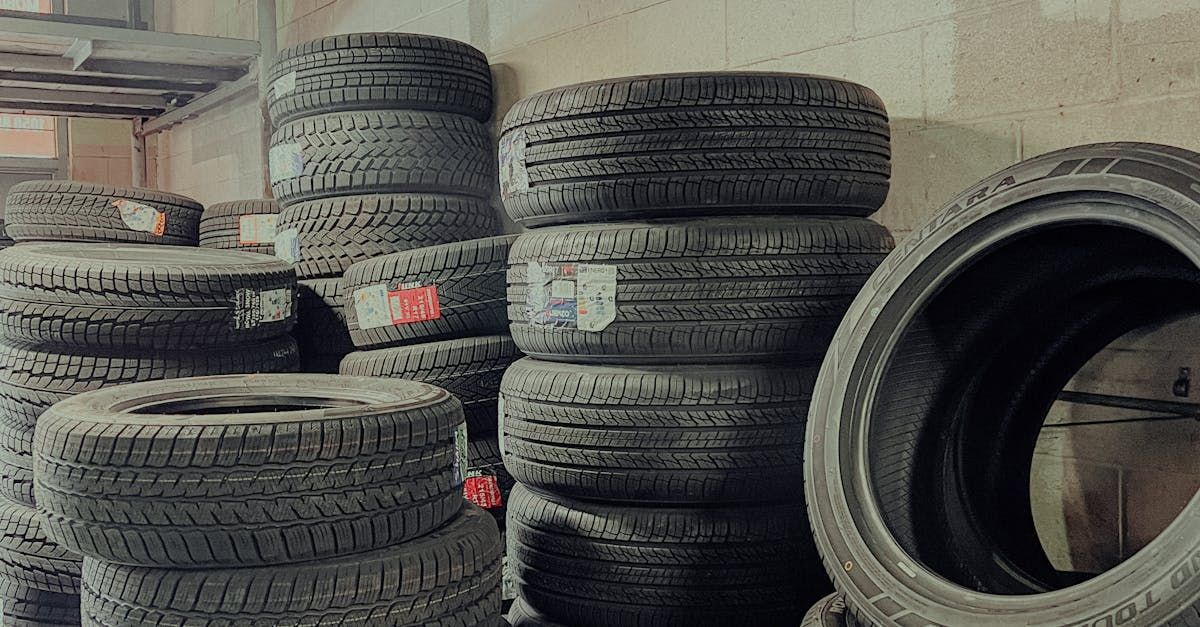 A bunch of tires are stacked on top of each other in a garage.