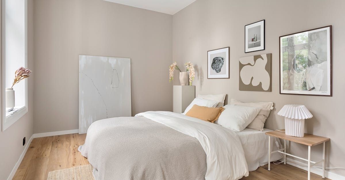 A bedroom with a bed , nightstand , and paintings on the wall.