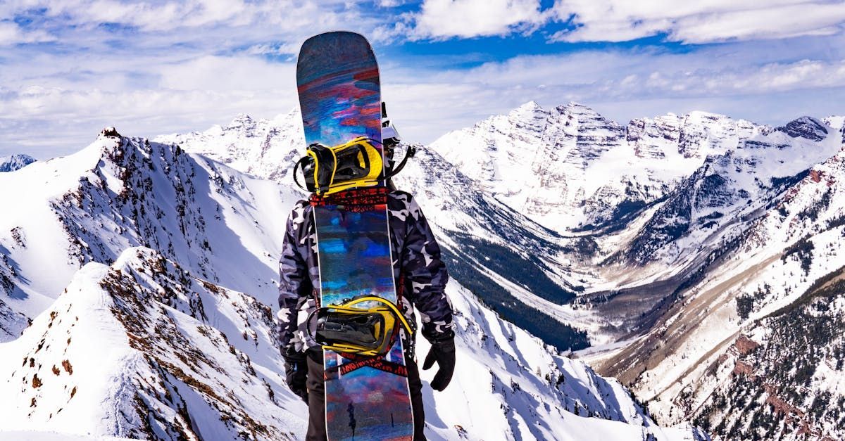 A person is holding a snowboard on top of a snow covered mountain.