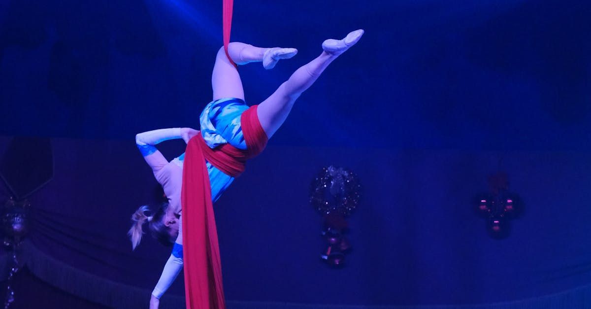 A woman is doing aerial acrobatics on a red cloth on a stage.