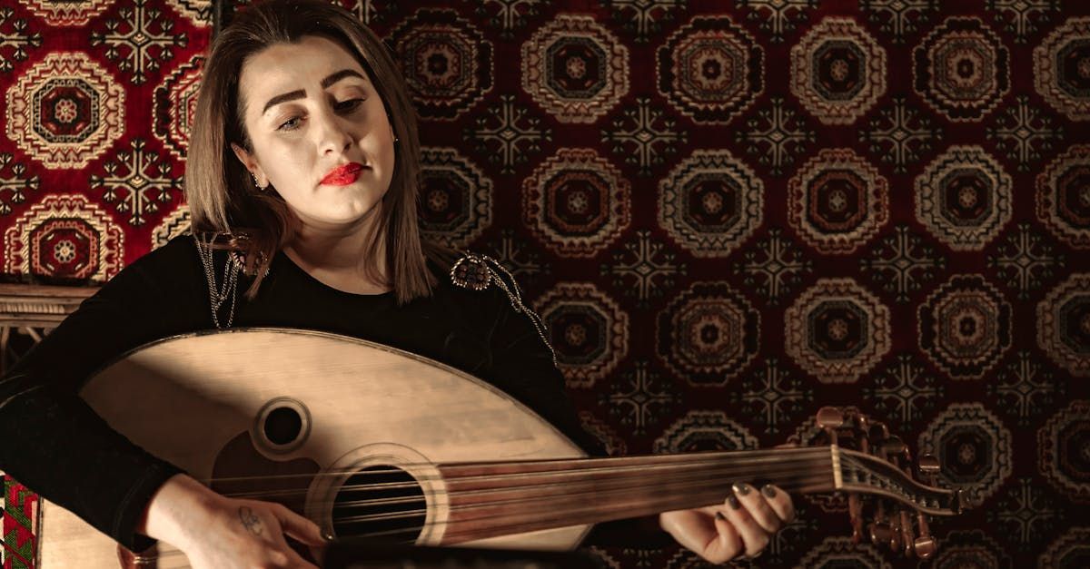 Une femme joue de la guitare devant un mur à motifs.