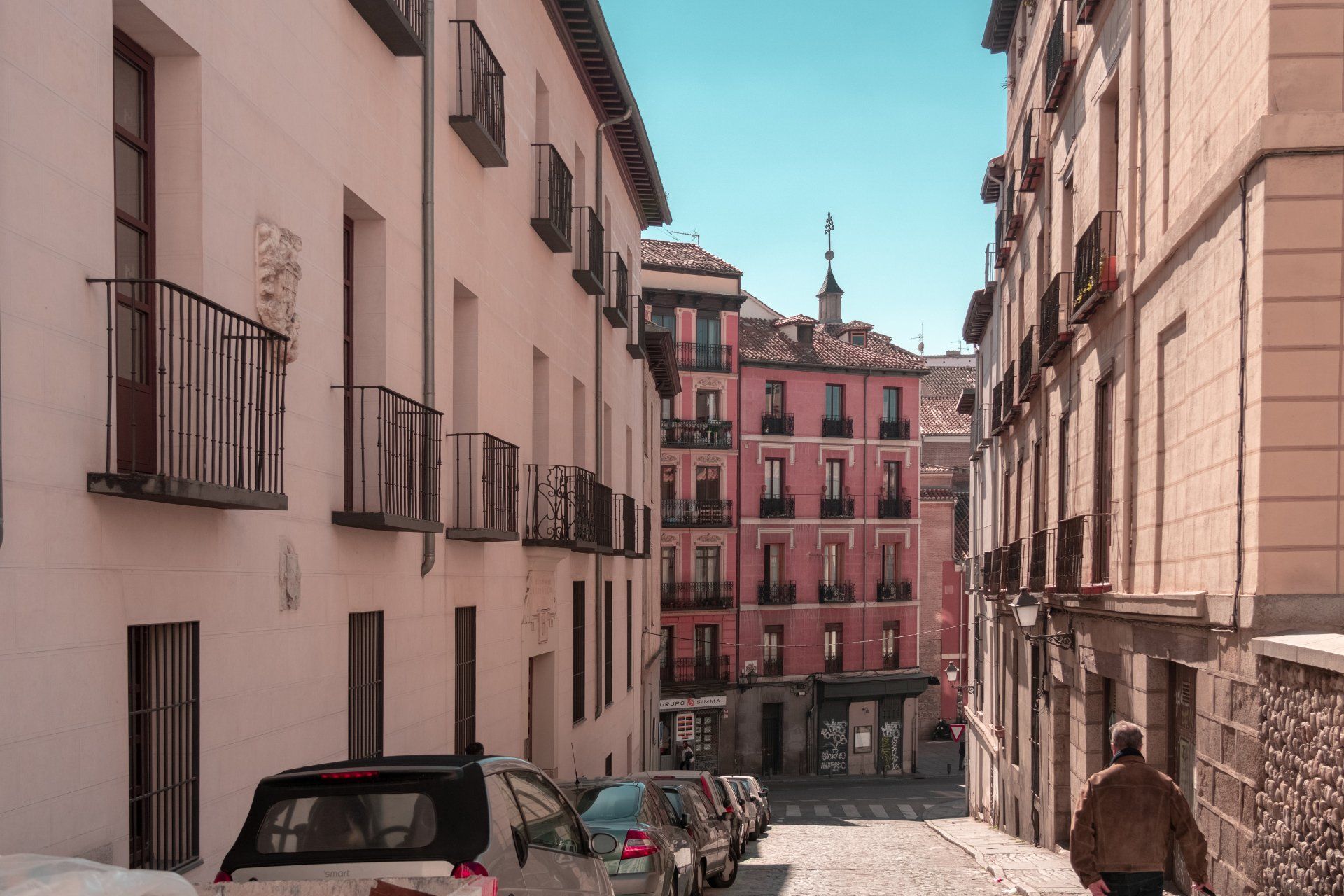 A man is walking down a narrow street between two buildings.