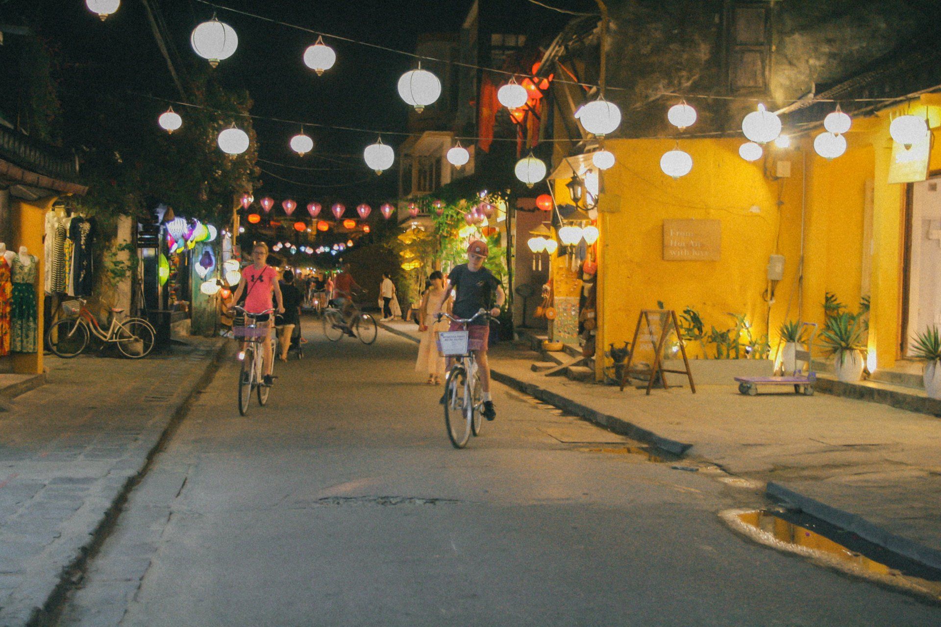 A couple of people are riding bicycles down a street at night.