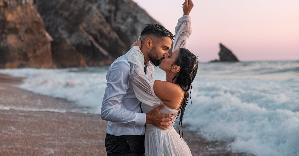 Bride and groom kissing on the beach with ocean backdrop
