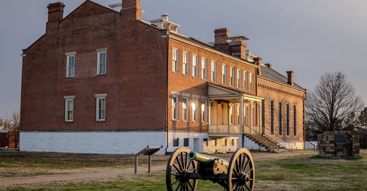 A cannon is sitting in front of a large brick building.