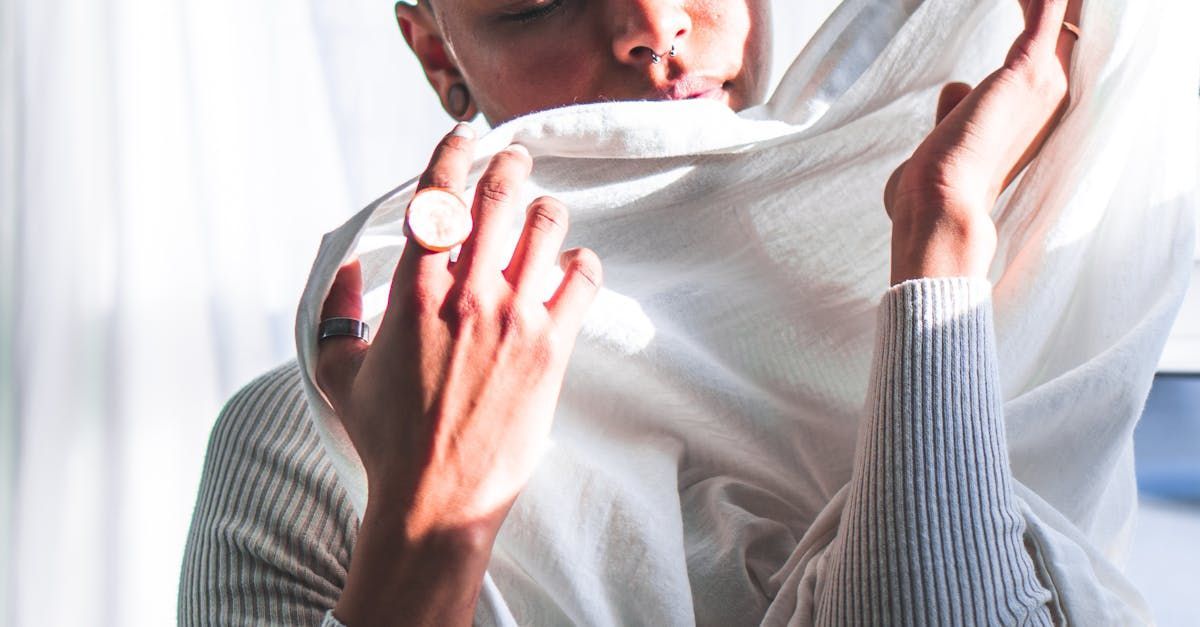 A woman is covering her face with a white scarf.