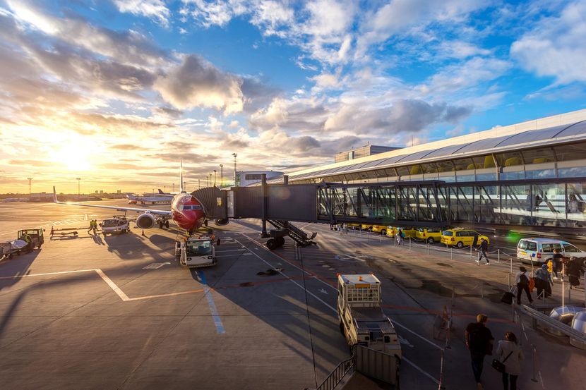 An airplane is being loaded at an airport at sunset.