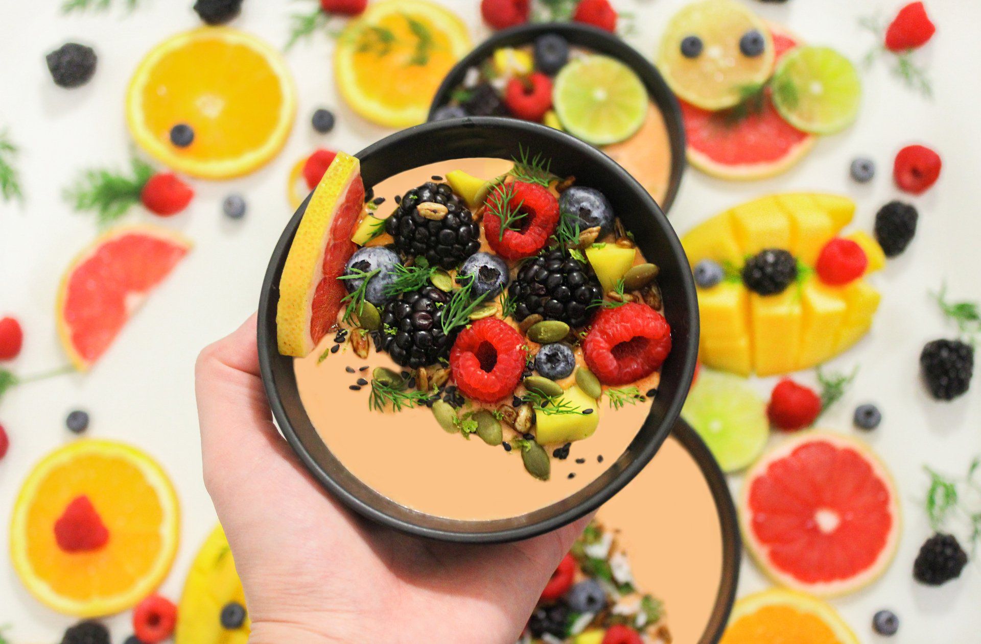 A person is holding a bowl of fruit in their hand.