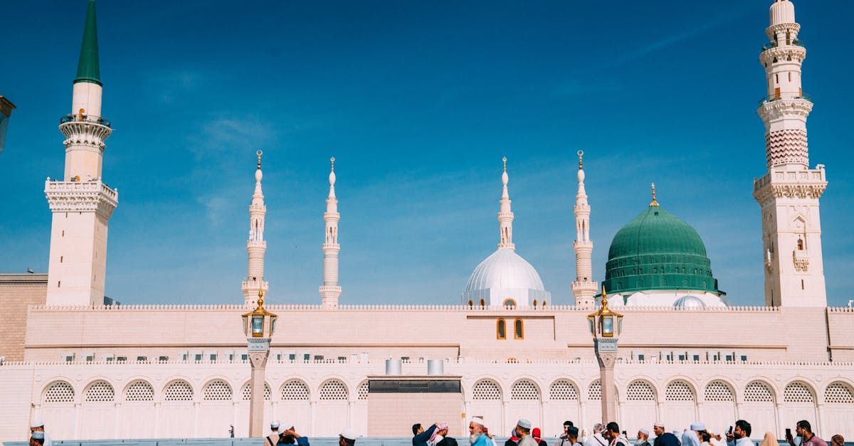 A group of people are standing in front of a mosque with a green dome.