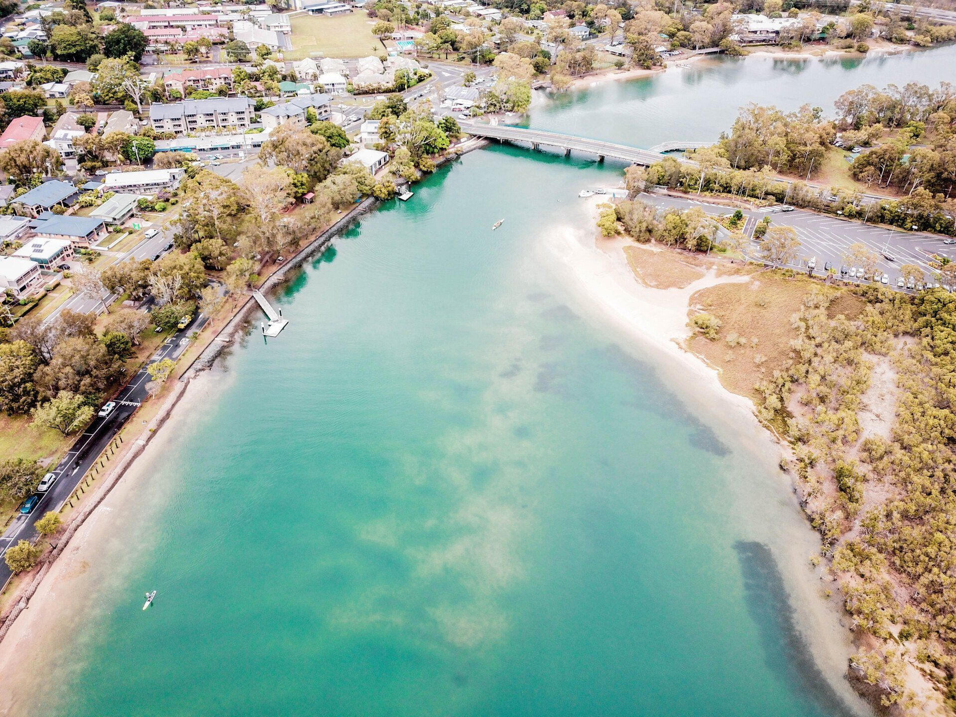 An Aerial View Of A River Surrounded By Trees And Houses — Appian Roads In Bundaberg, QLD
