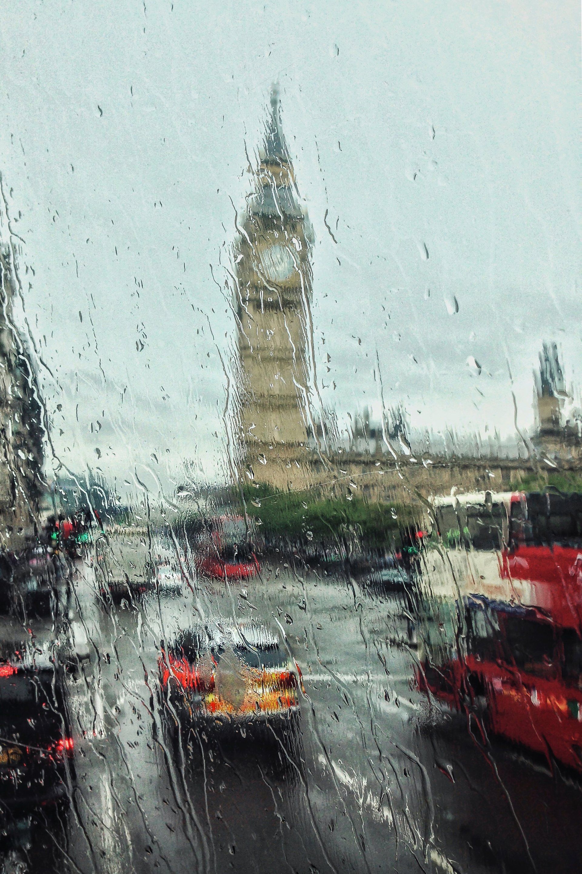 The big ben clock tower is visible through the rain drops on the window.