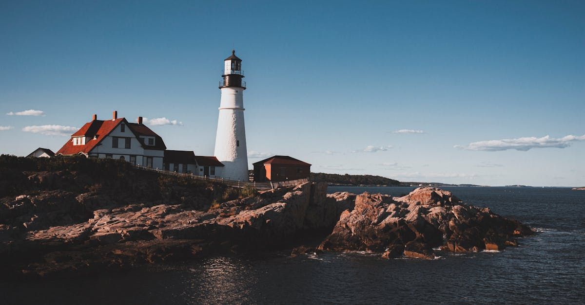 A lighthouse is sitting on top of a rocky cliff overlooking the ocean.