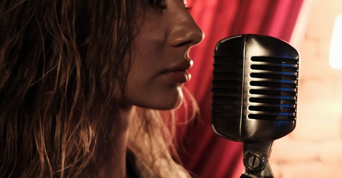 A woman is singing into a microphone in front of a red curtain.