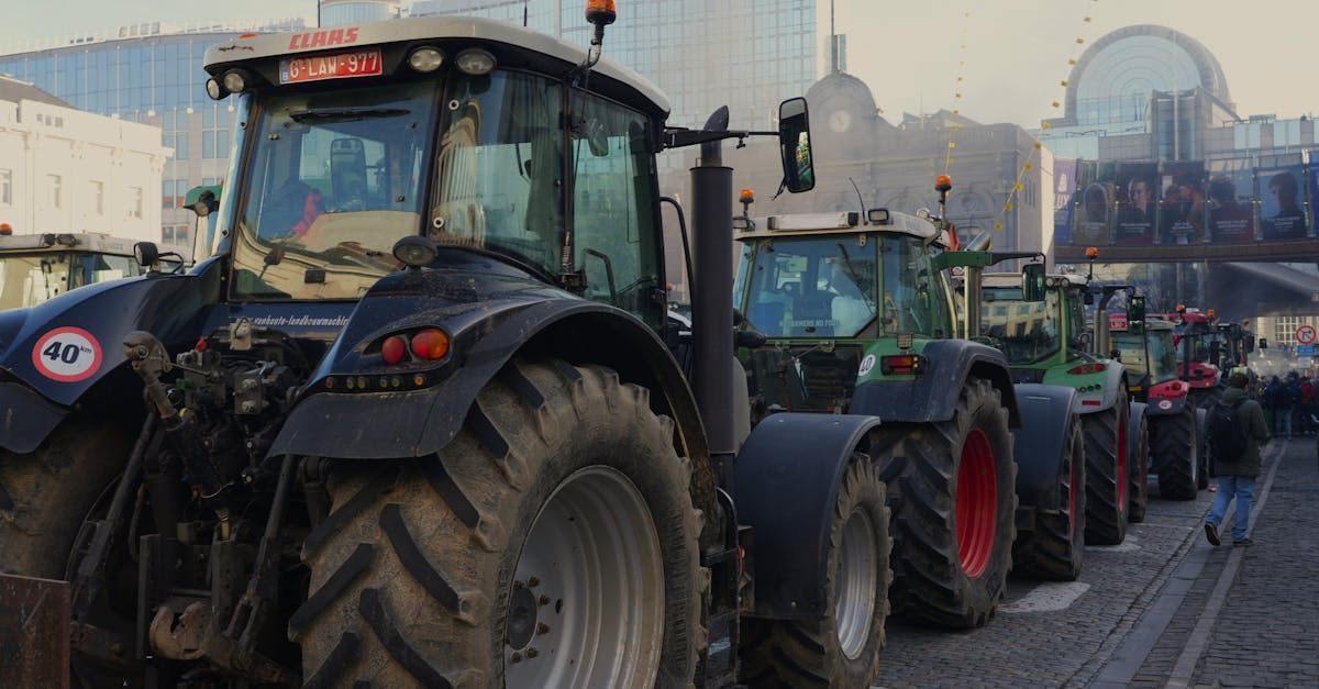 A row of tractors are driving down a city street.