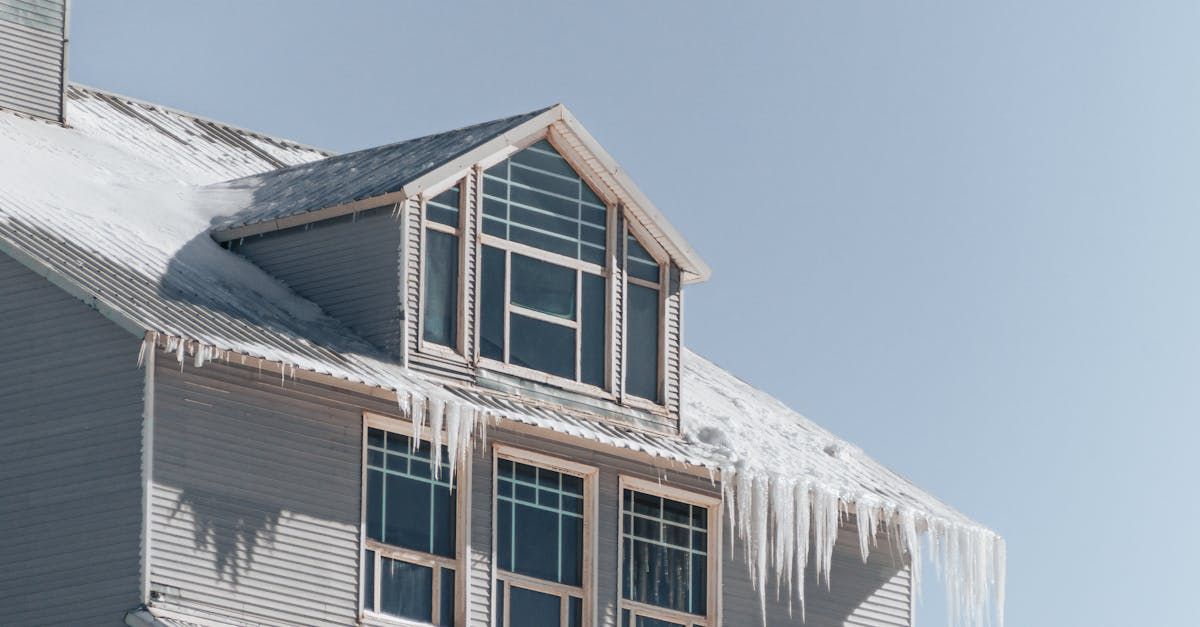 The roof of a house is covered in snow and icicles.