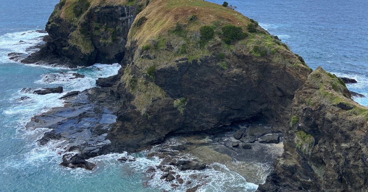 A rocky cliff overlooking the ocean with waves crashing on it.