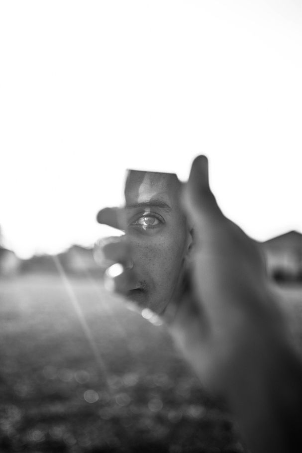 A black and white photo of a person holding a broken mirror.