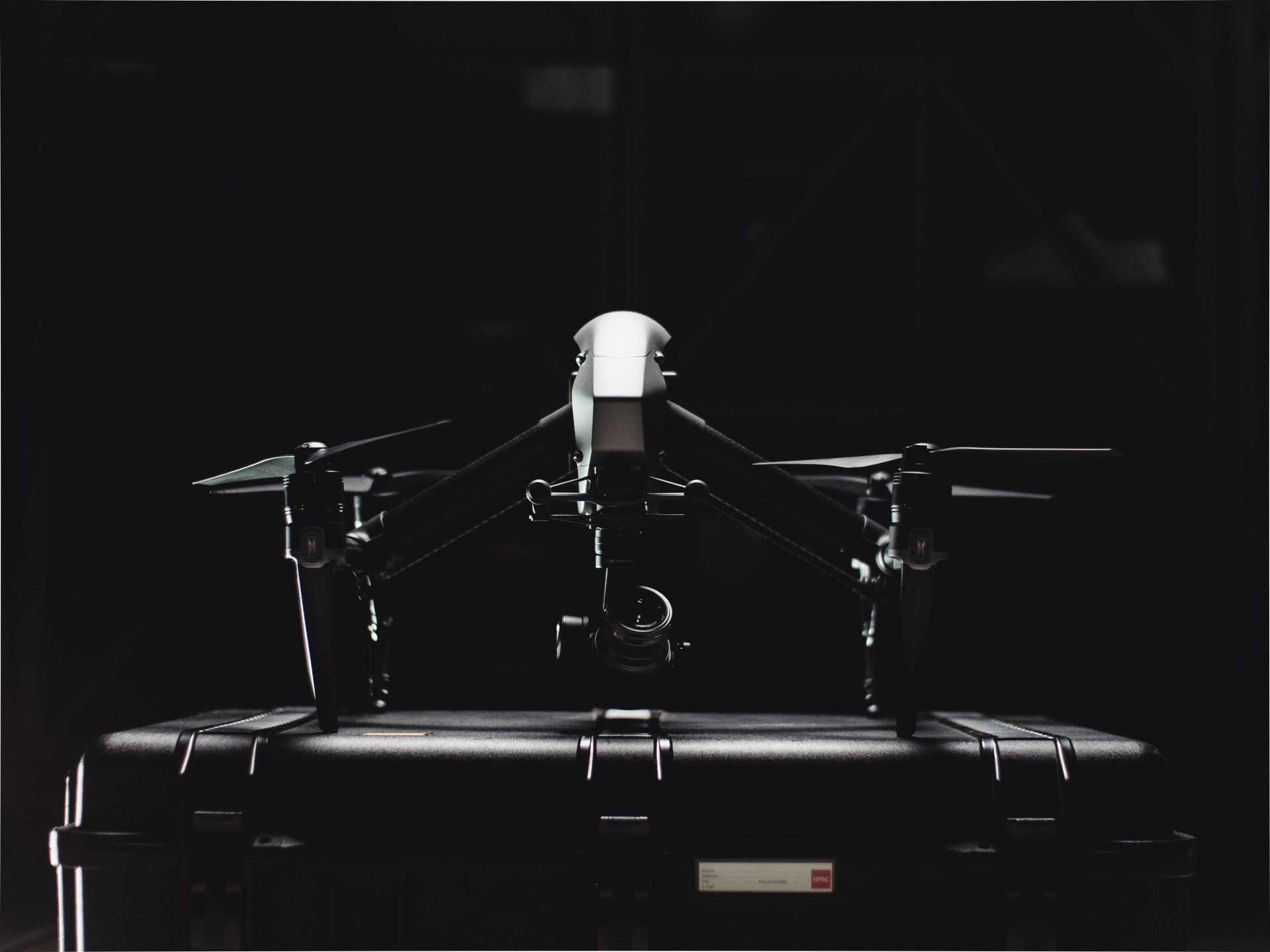 A drone is sitting on top of a black case in the dark.