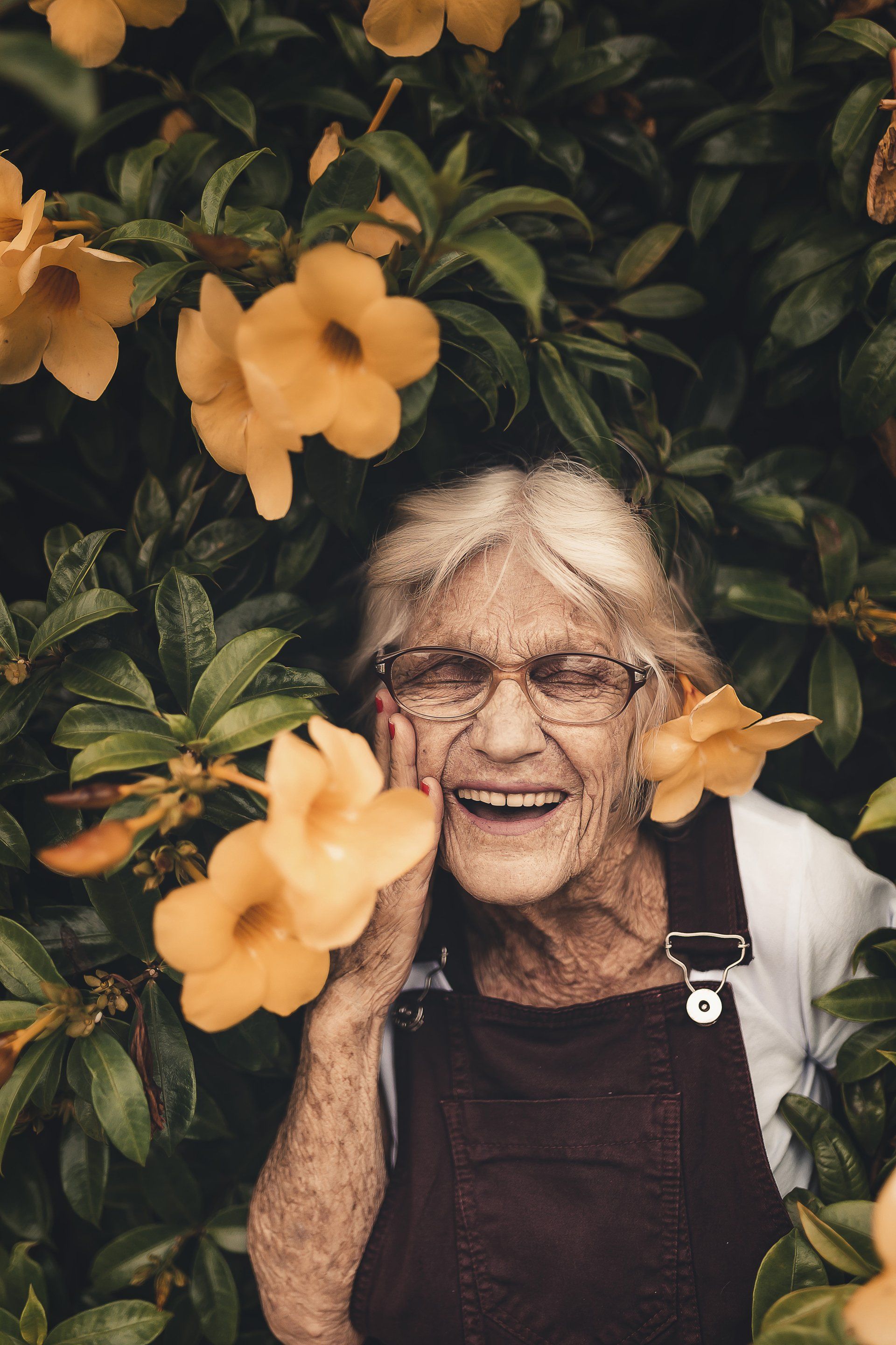 elderly woman with glasses smiling showing dentures
