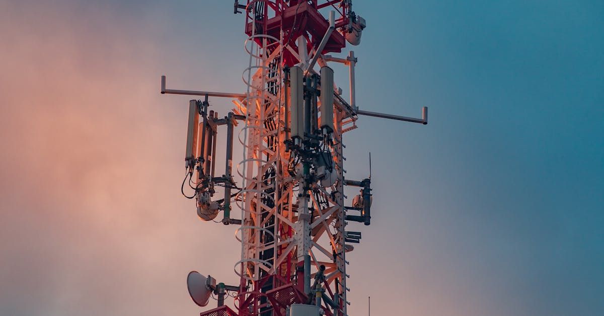 Een rode en witte telefoontoren tegen een bewolkte hemel.