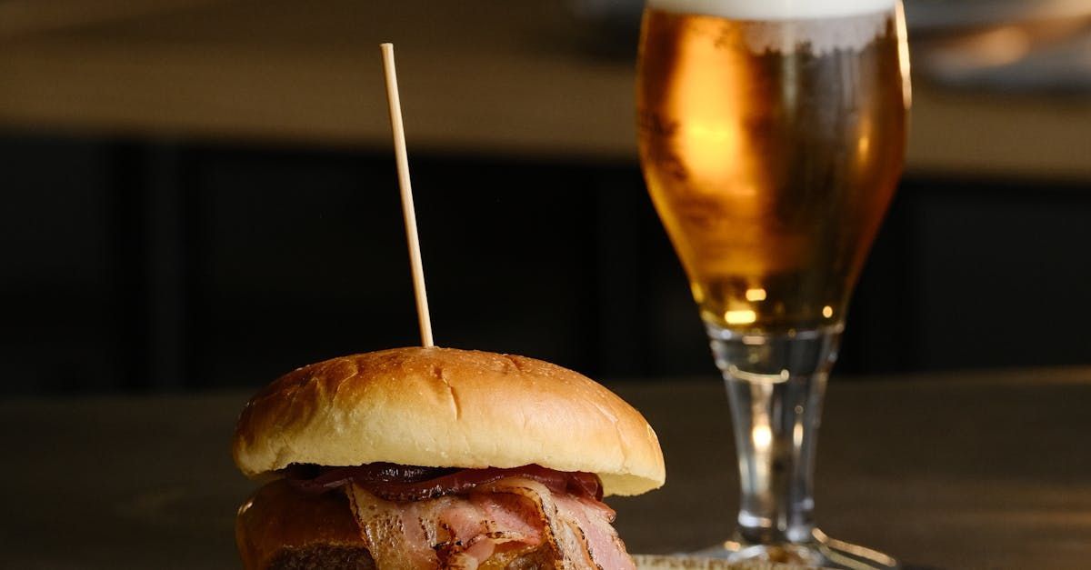 A hamburger and a glass of beer are on a table.