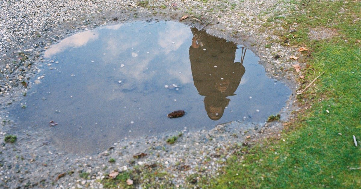 A puddle of water in a pothole with a reflection of a building in it.