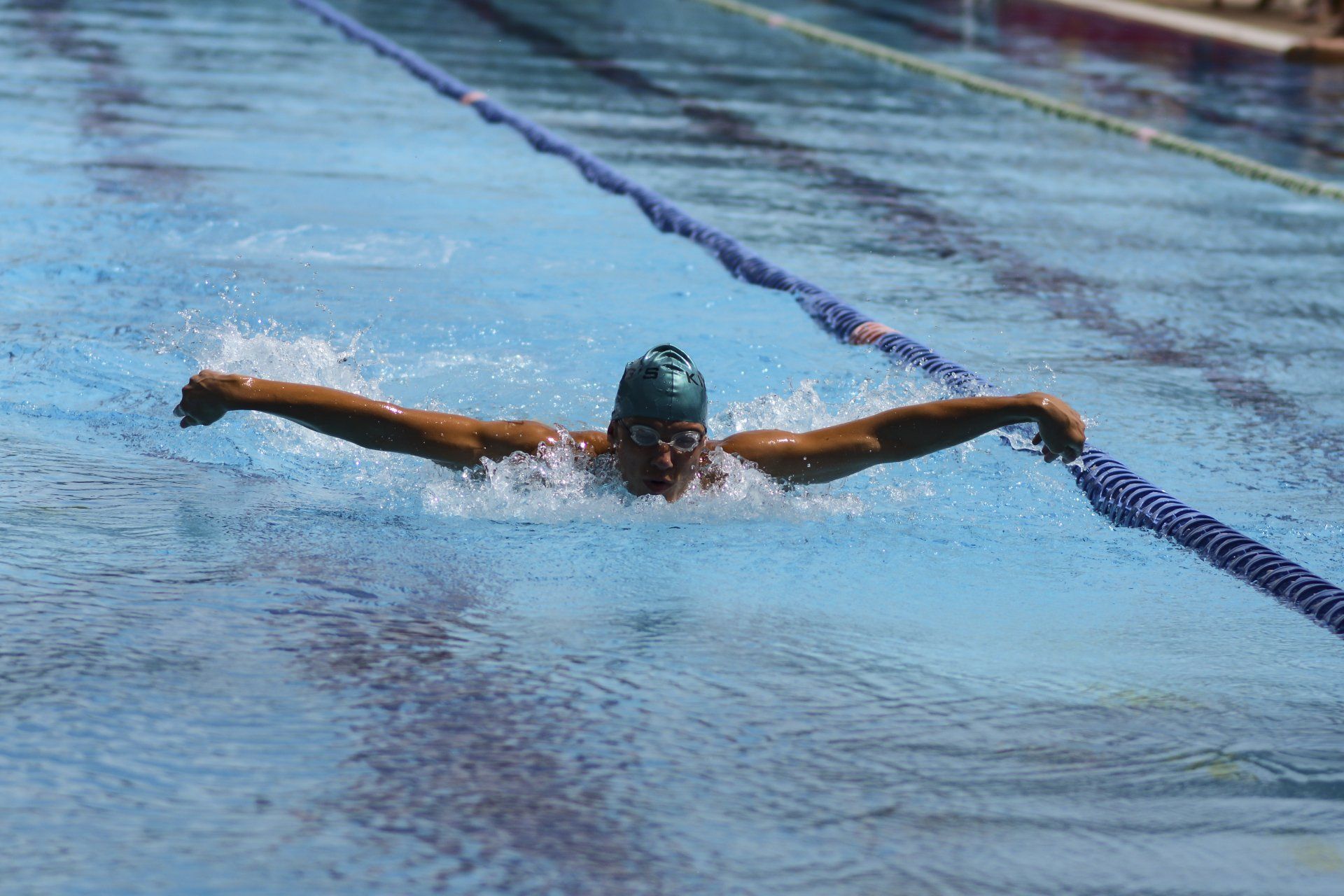 A young girl is giving a thumbs up in a swimming pool.