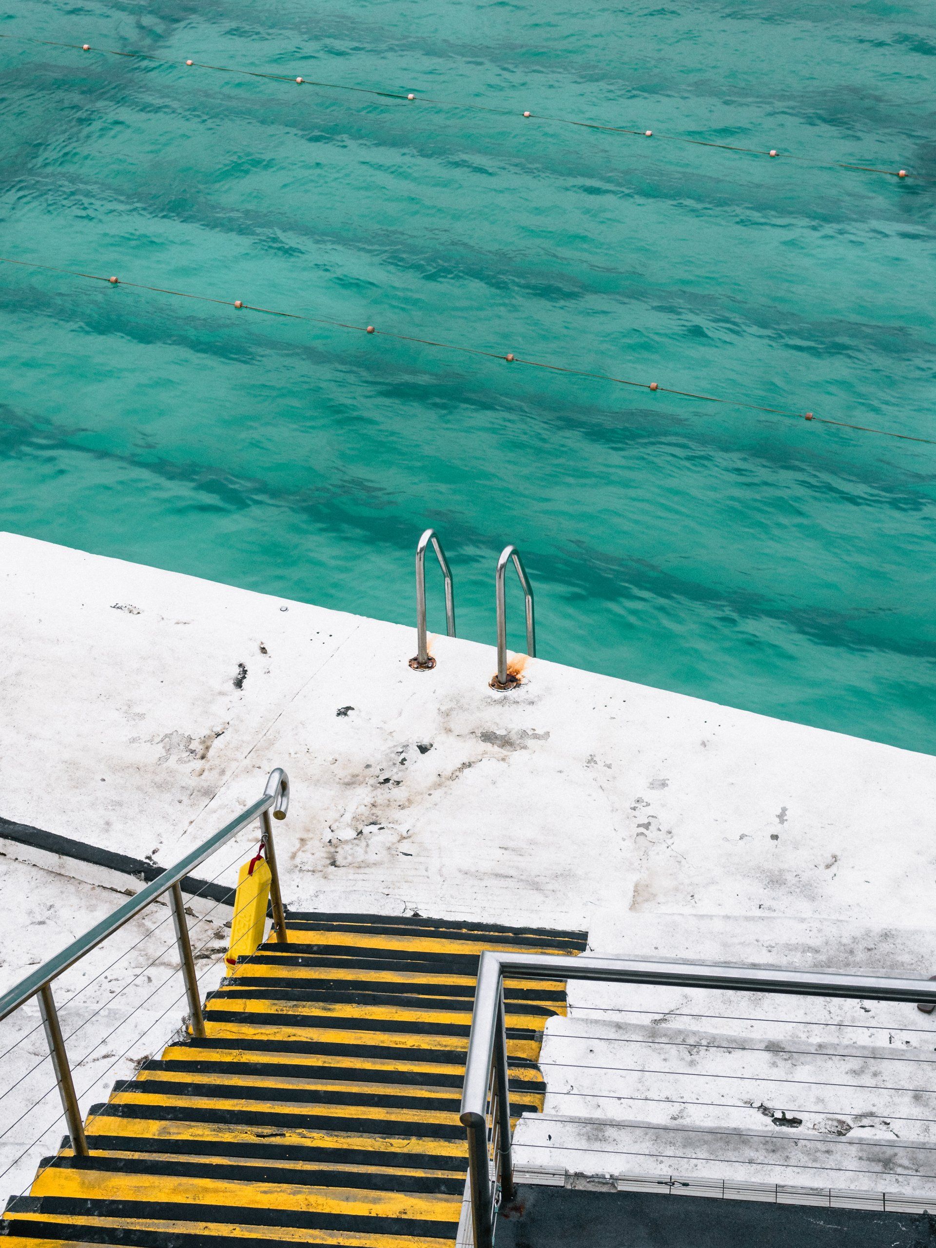 A set of yellow and black stairs leading to the ocean.