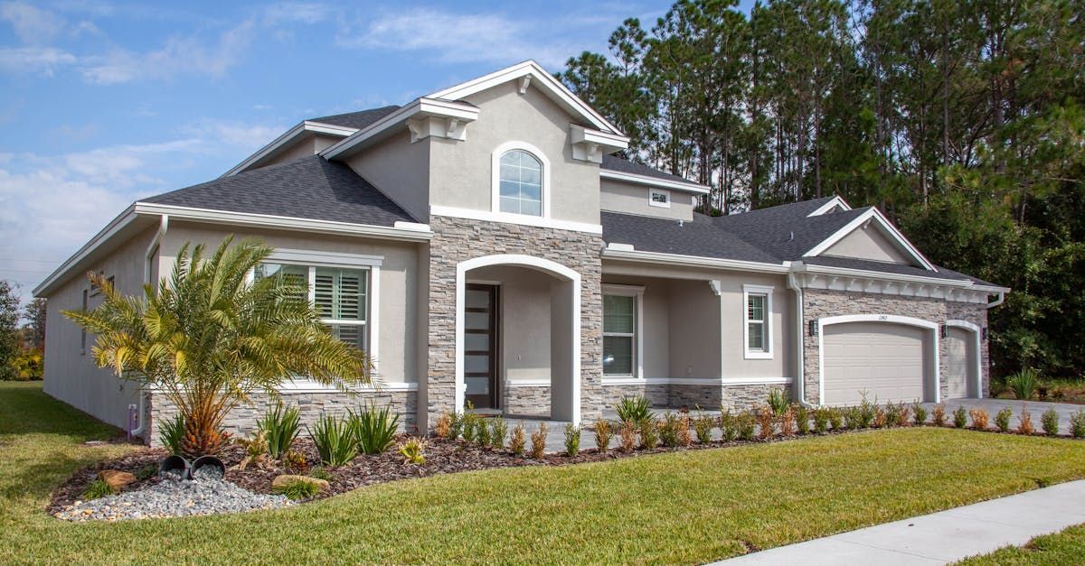 A large white house with a gray roof is sitting on top of a lush green lawn.