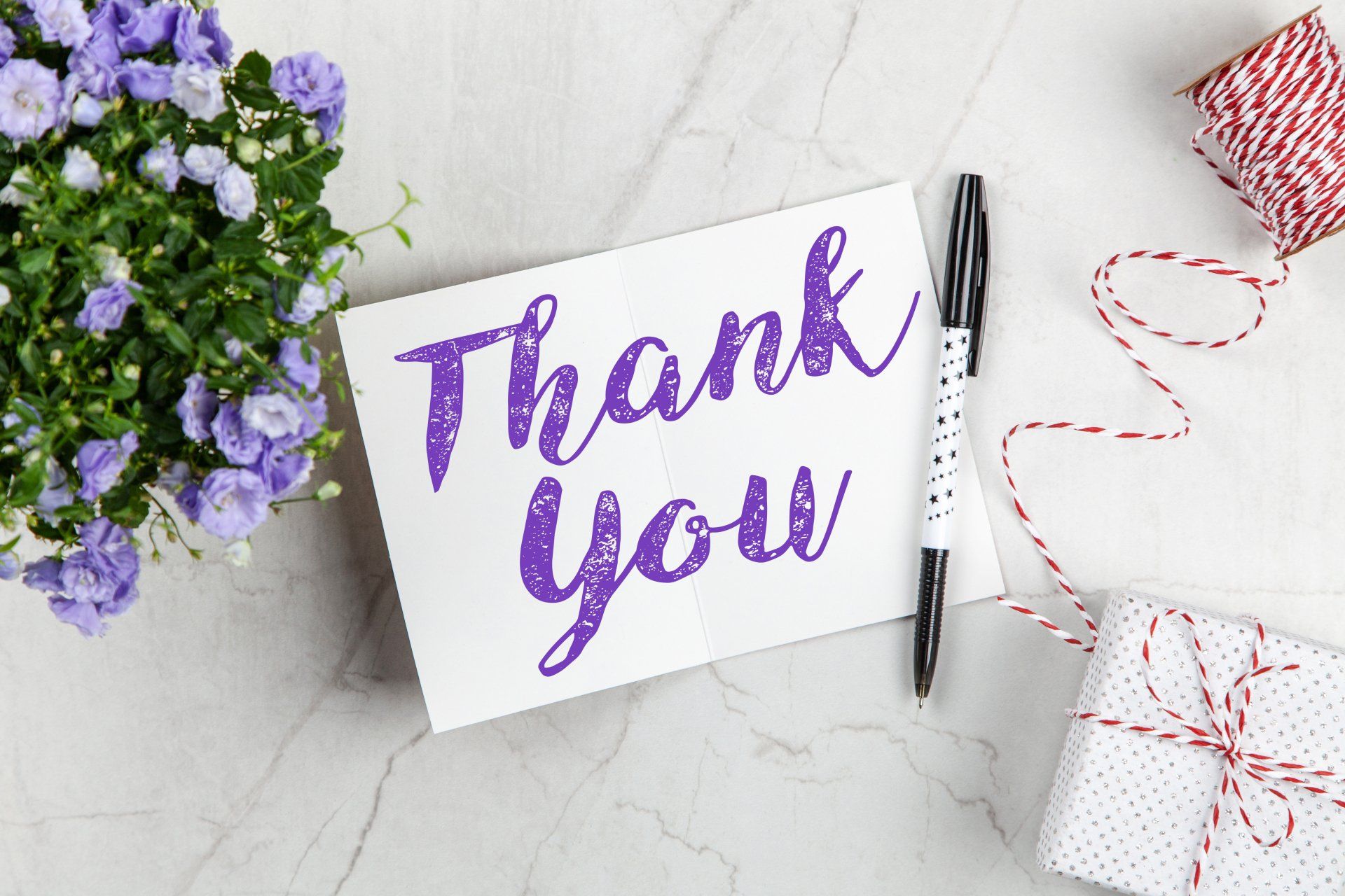 The words Thank You written in purple on a small note card.