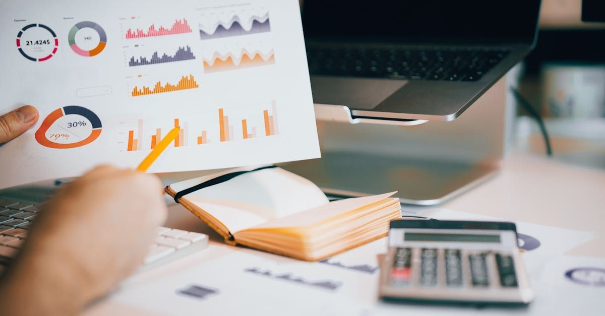 Une personne tient un morceau de papier avec un graphique dessus devant un ordinateur portable.