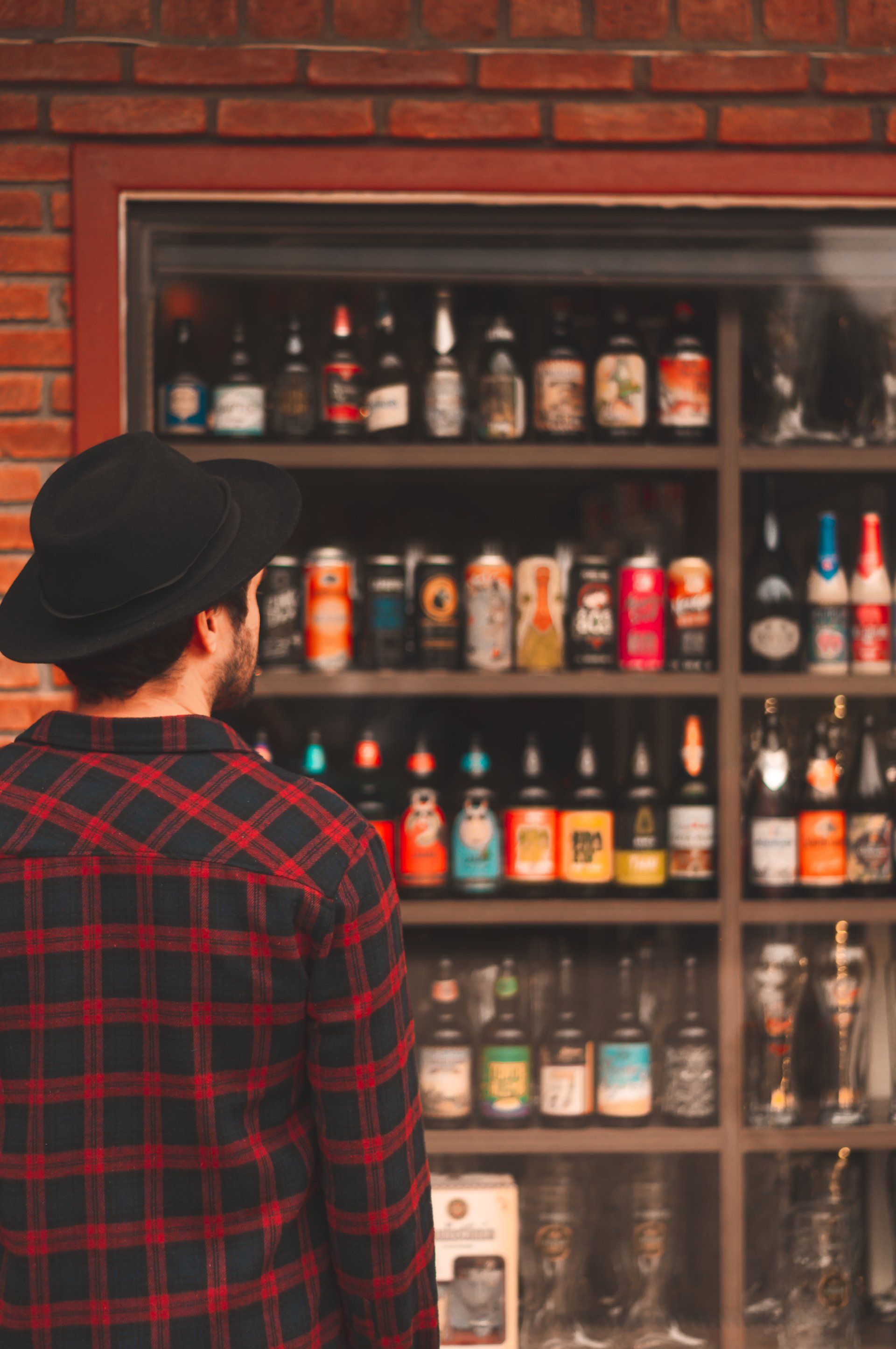 A man is standing in front of a shelf full of beer bottles.