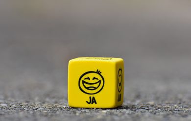 Yellow die with a smiling face and the word