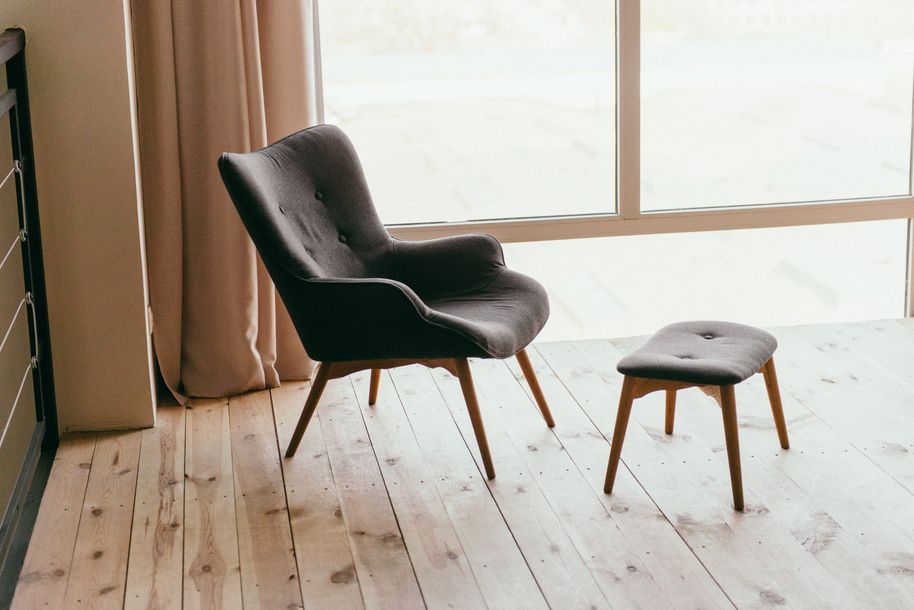 A chair and ottoman are sitting on a wooden floor in front of a window.