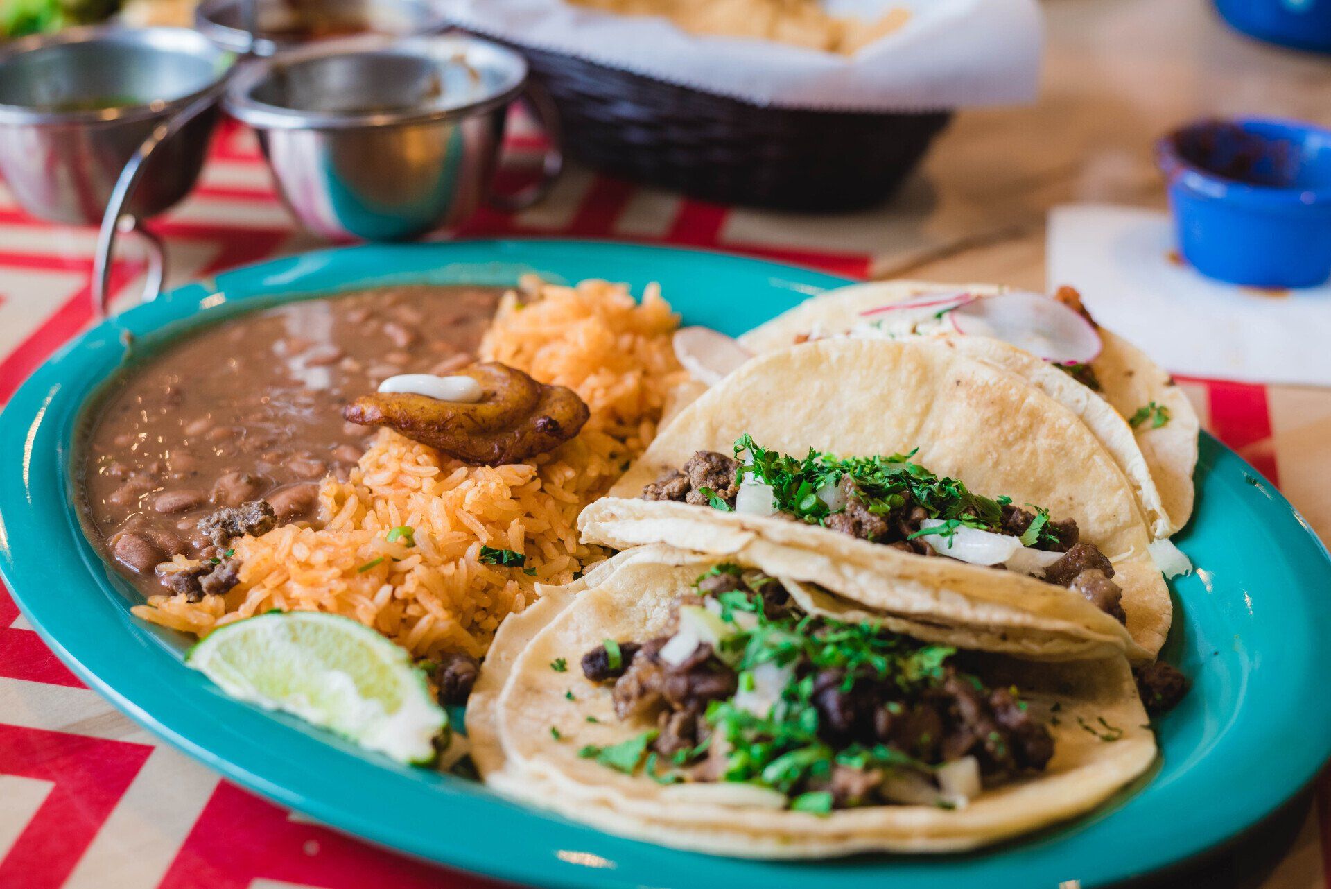 A plate of tacos , rice and beans on a table.