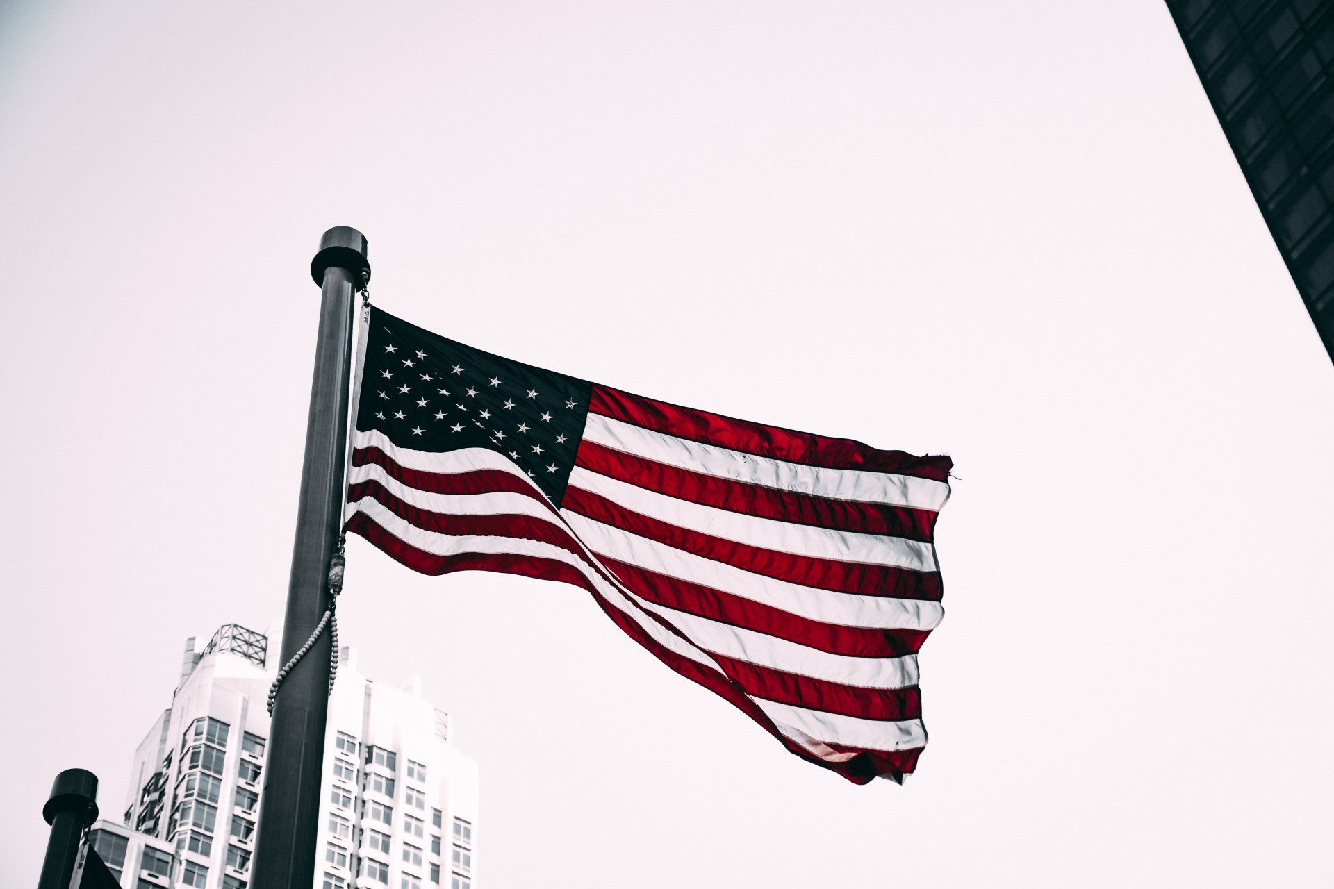 an american flag is flying in front of a tall building