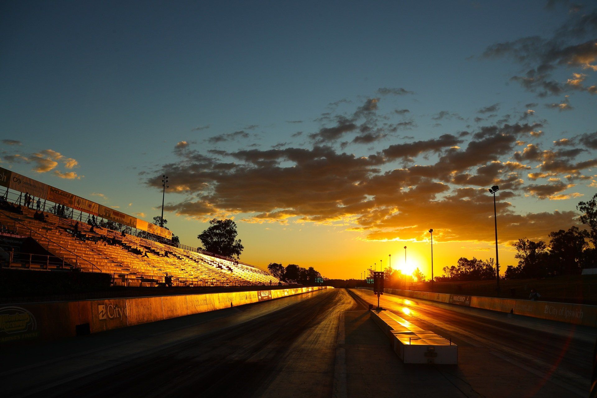 A race track at sunset with the sun shining through the clouds