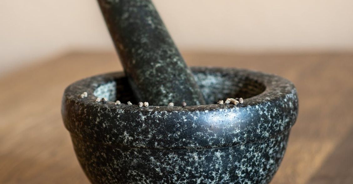 A mortar and pestle is sitting on a wooden table.