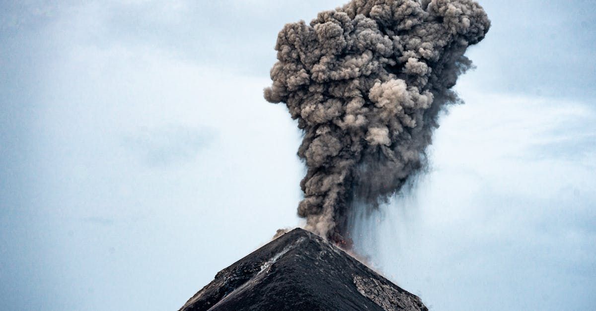 A volcano is erupting with smoke coming out of it.
