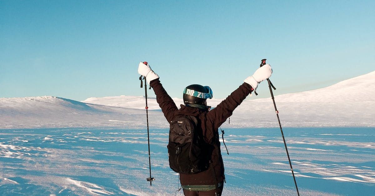 A person is standing on top of a snow covered mountain with their arms in the air.