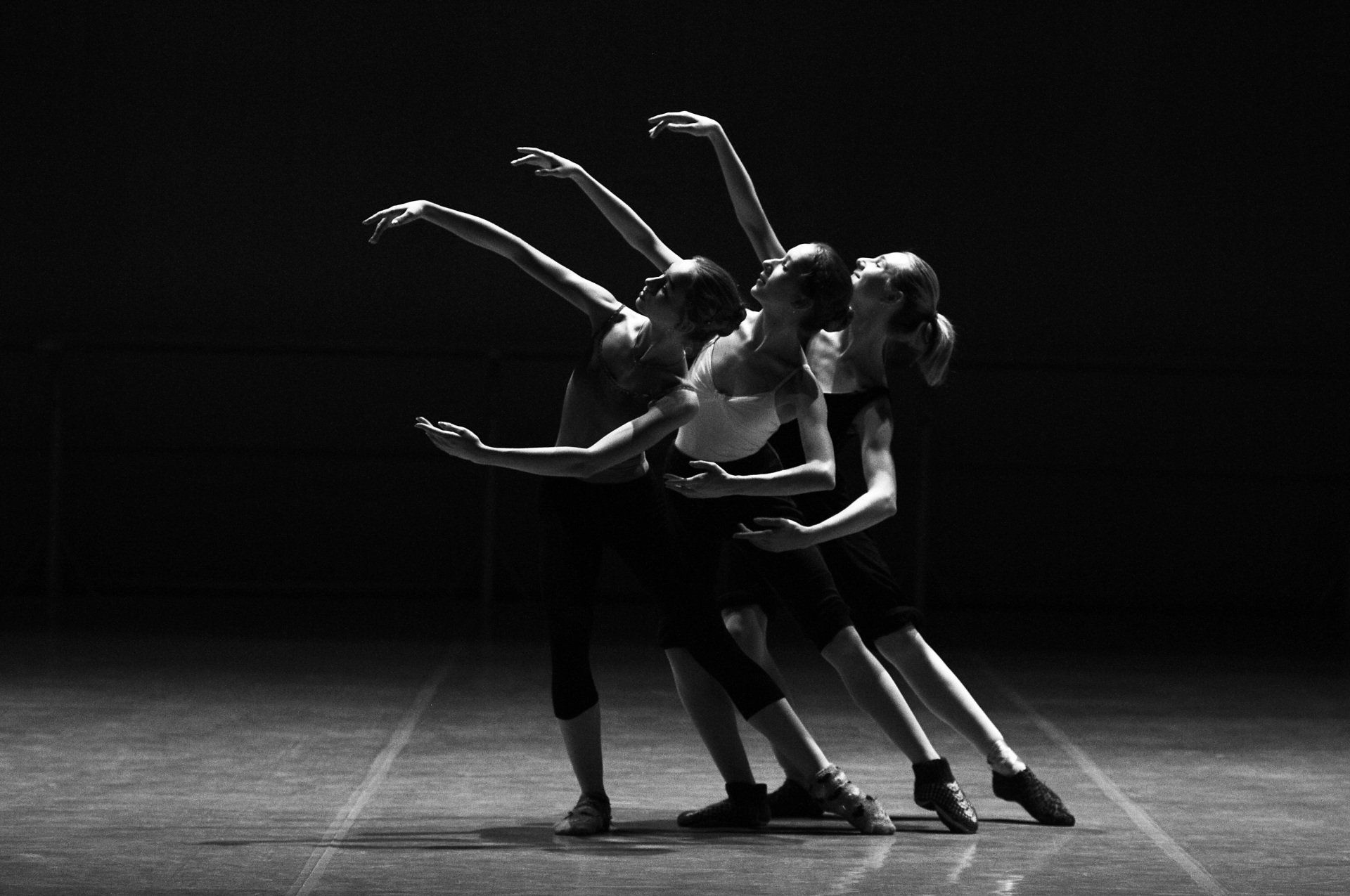 Four people with raised arms, appearing to perform a synchronized dance or group activity.