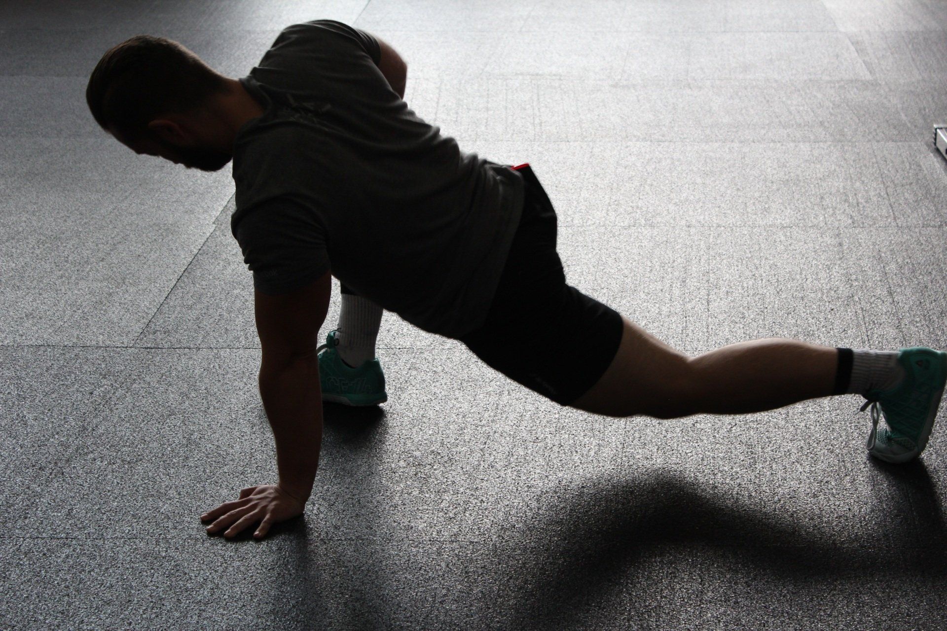 A man is doing push ups on the floor in a gym.