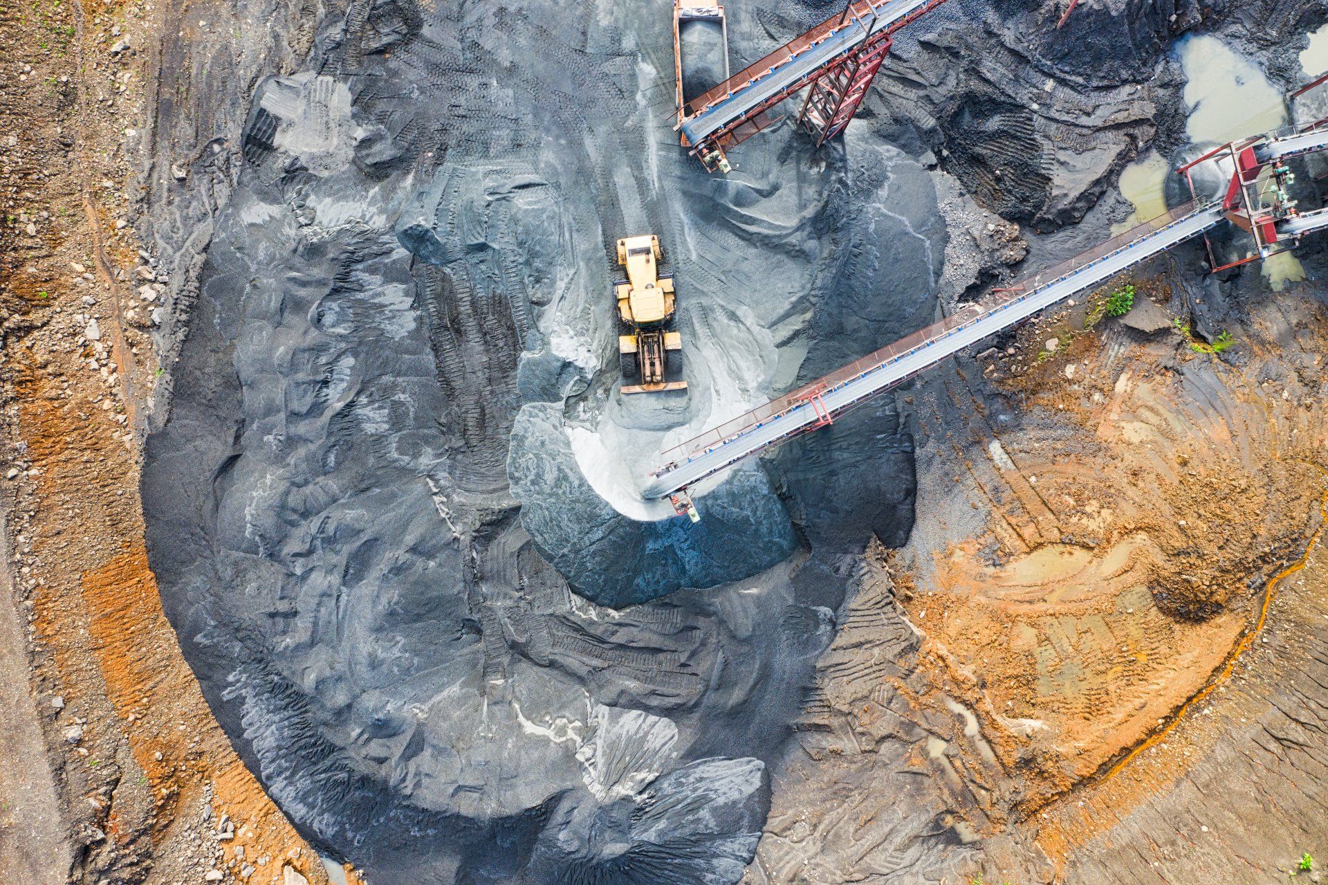 An aerial view of a coal mine with a bulldozer and conveyor belts.