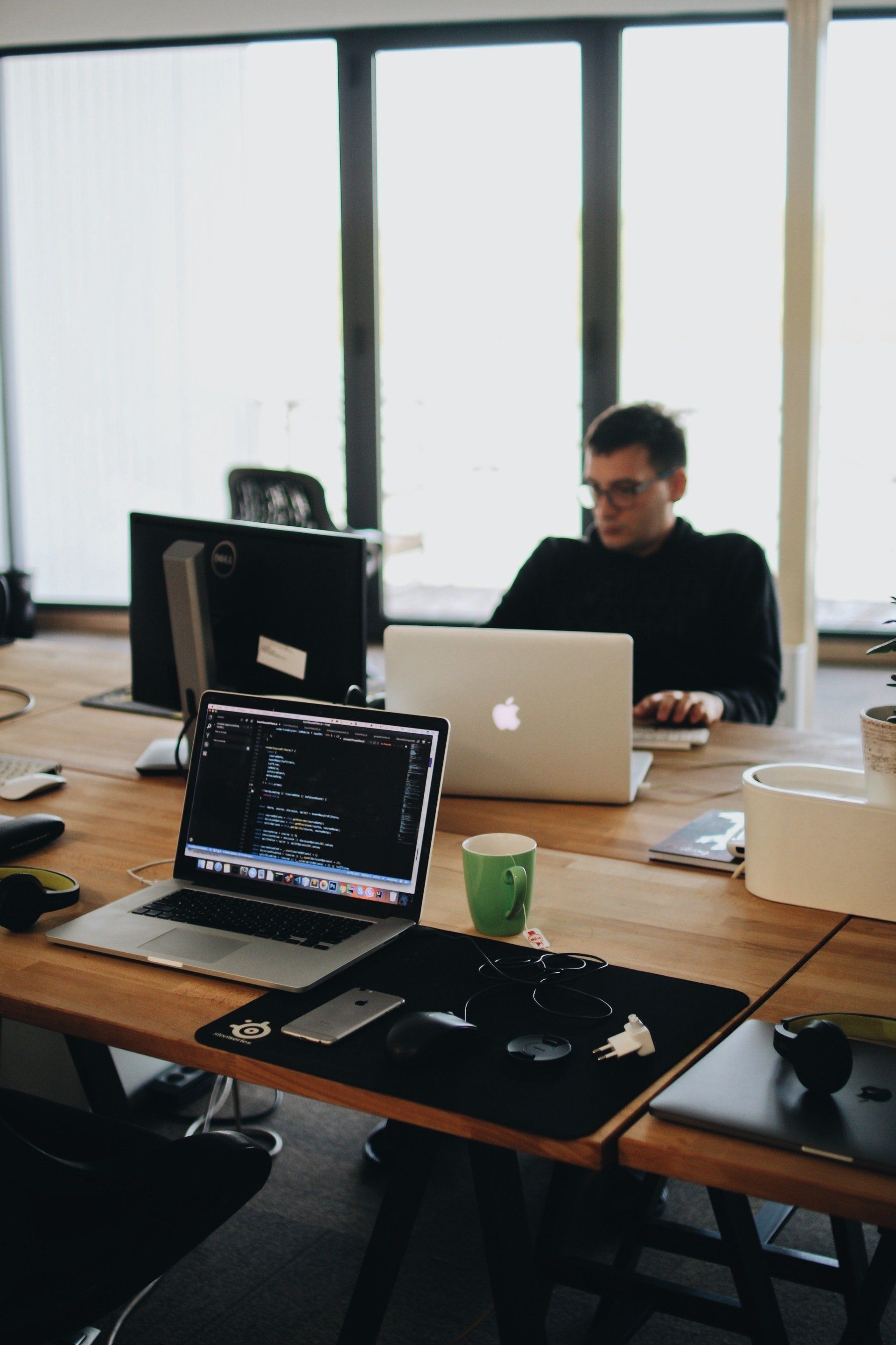 a man sits at a desk with an apple laptop