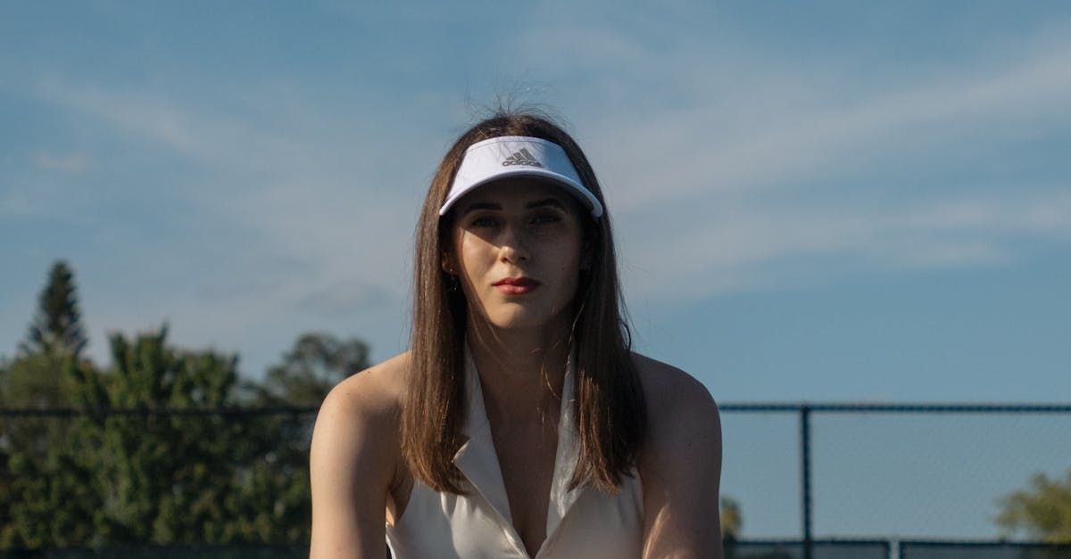 A woman wearing a visor and a white shirt.