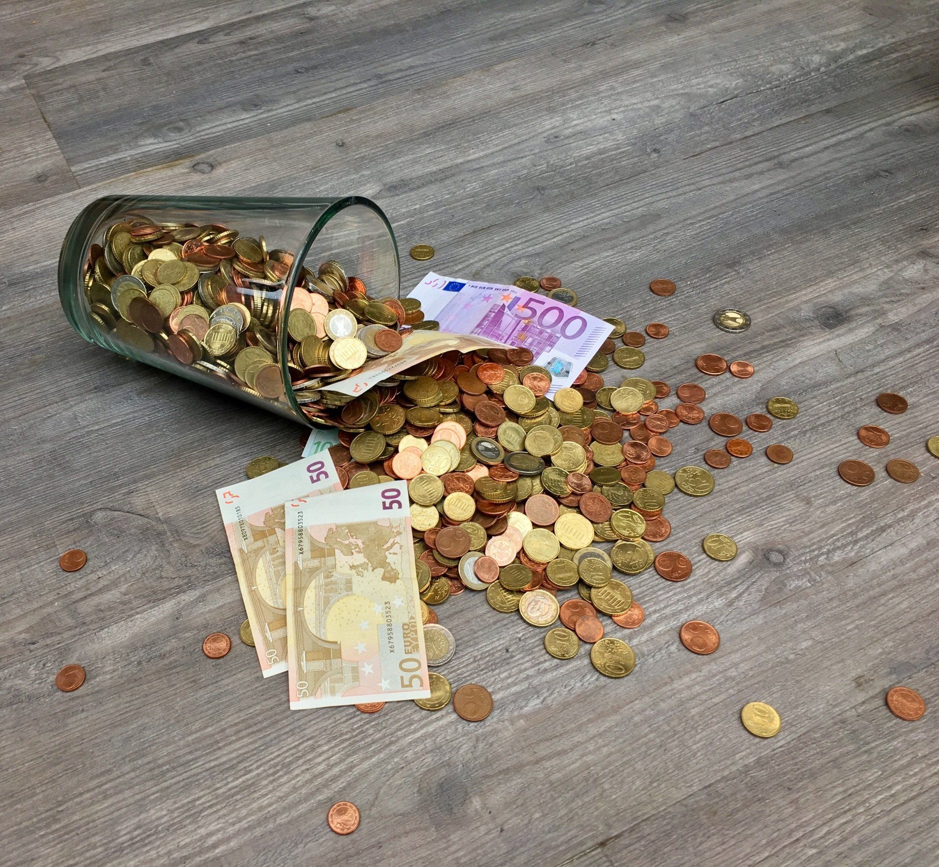 Een glazen pot gevuld met munten en een biljet van 500 euro