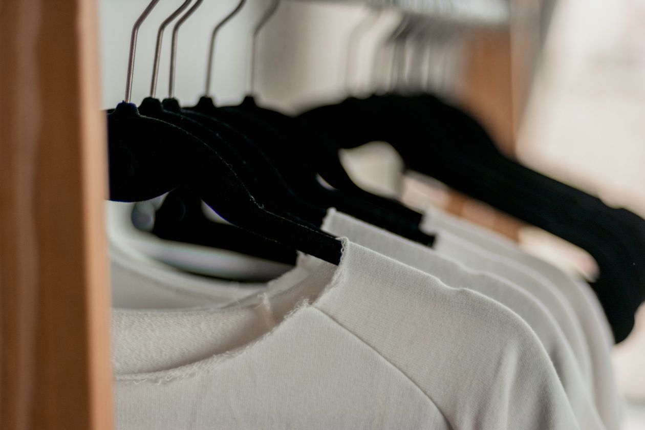 A close up of clothes hanging in a closet.