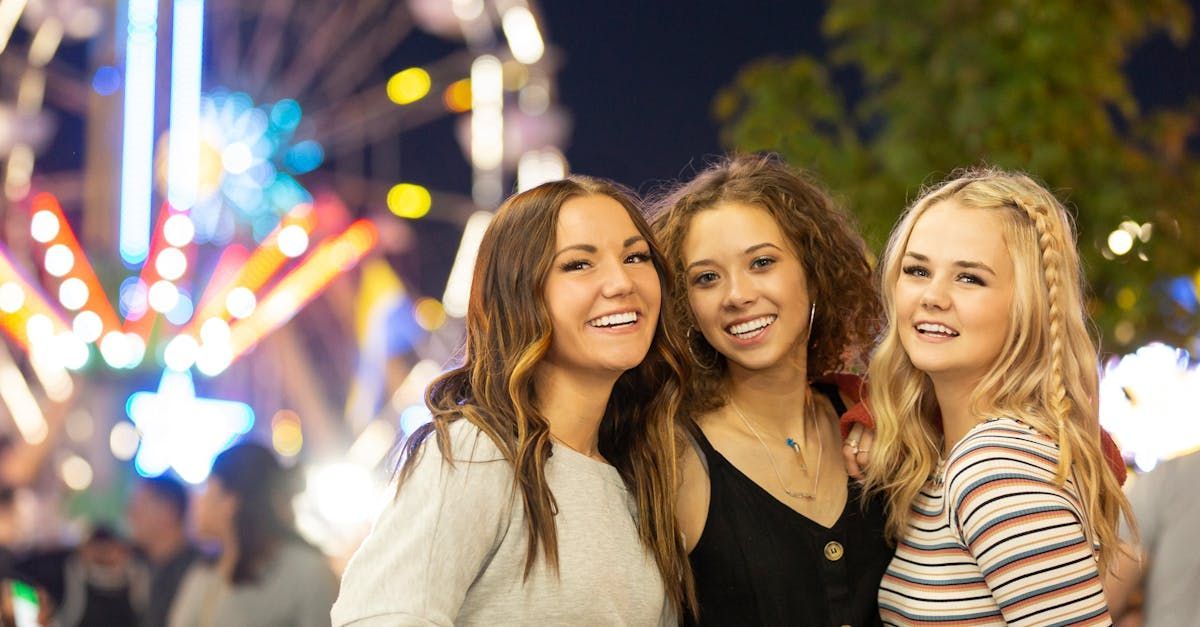 Three young women are posing for a picture at a carnival.