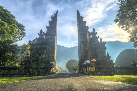 A group of people are standing in front of a large stone gate.