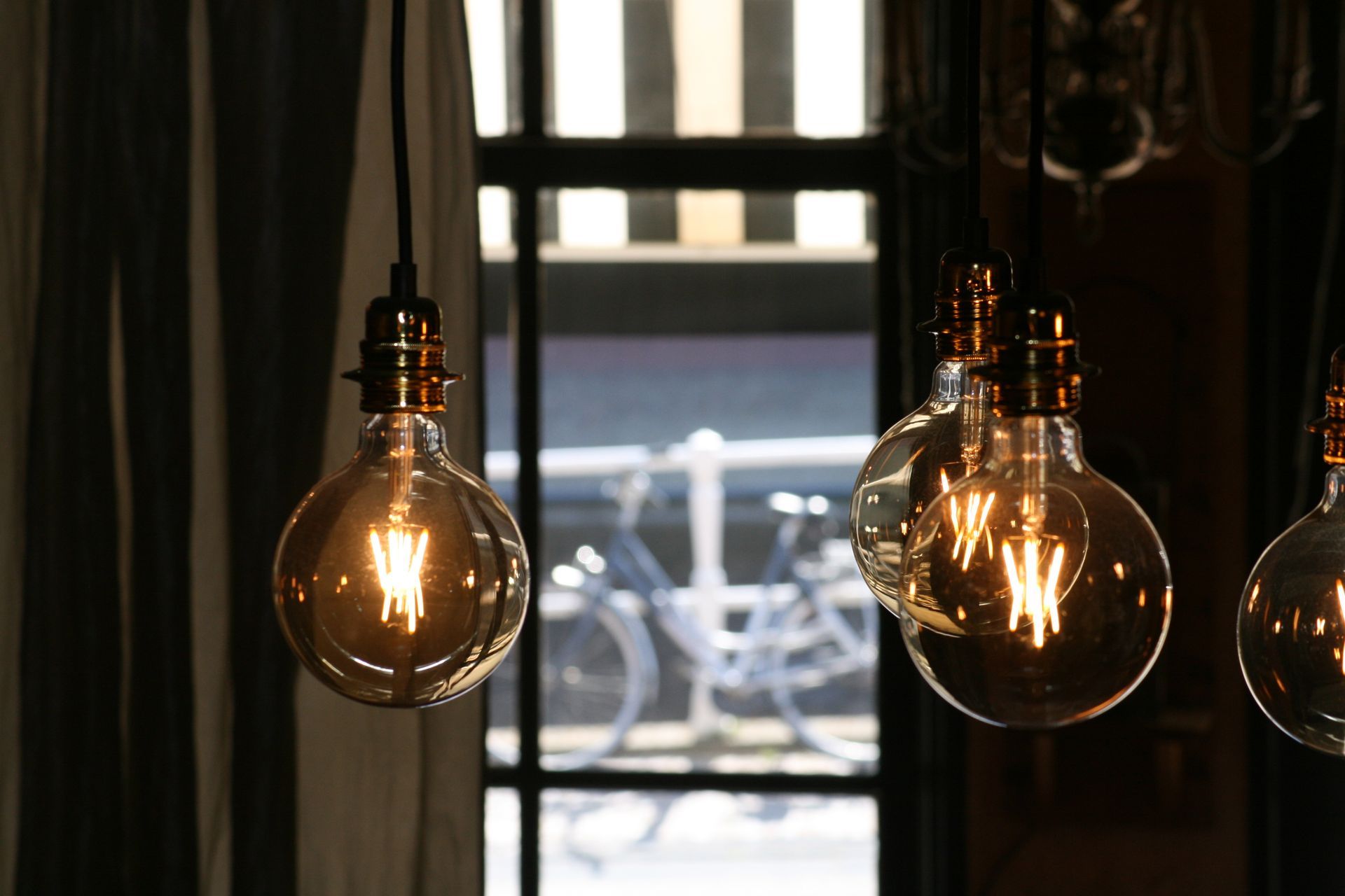 A bunch of light bulbs hanging from the ceiling in front of a window.